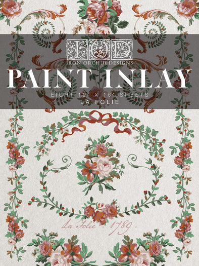 Front packaging of IOD La Folie Paint Inlay featuring floral and ribbon details