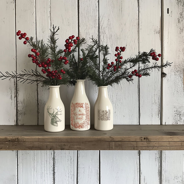 Three white vases decorated with deer, Christmas carol, and wreath designs from Twelfth Night Inlay.