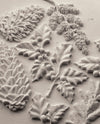 Styled castings from the IOD Winter Forage Mould showing pinecones, holly, and winter botanicals.